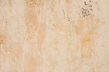 Grunge background of cracked peeling walls with peeled putty in beige tones.