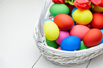 Easter Eggs in basket and spring flowers on white wooden table
