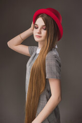 Girl in a gray strict dress in a red hat with narrow brim