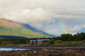 small houses on the shore of the fjord and a rainbow in the sky