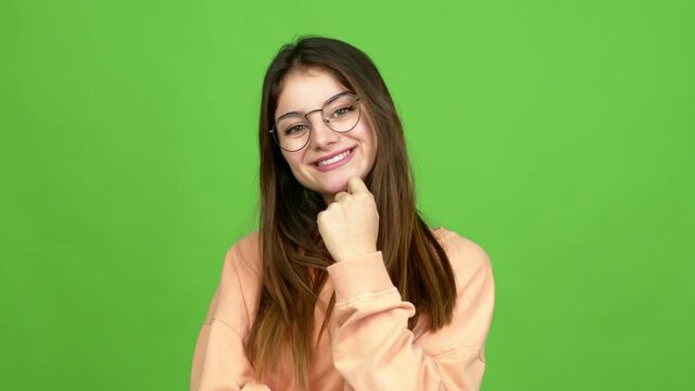 Young caucasian woman with glasses smiling and looking to the front with confident face over isolated background. Green screen chroma key