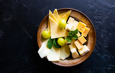 Cheese plate with grapes, and nuts on a wooden background