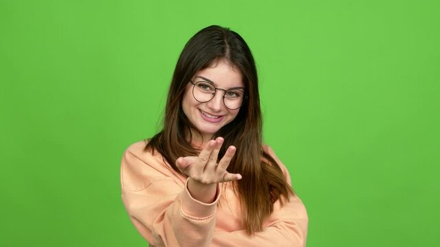 Young caucasian woman with glasses presenting and inviting to come with hand over isolated background. Green screen chroma key