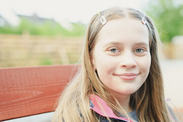 Outdoor portrait of cute blonde hair teenage girl looking at camera