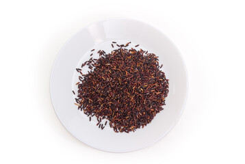Uncooked black rice on white dish, top view
