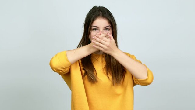 Young caucasian woman covering mouth with hands. Can not speak over isolated background