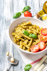 vegan pasta with homemade pesto sauce of basil, pine nuts and olive oil with cherry tomatoes. comfort food.