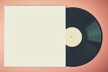Old retro vinyl disc in paper case on pink background, mockup. Vintage toned photo