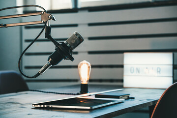 Studio audio podcast interior. Microphone, laptop and on air lamp on the table, close-up