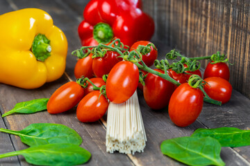 Closeup view of raw pasta spaghetti on wooden background.Colorful fresh organic vegetables with uncooked pasta , healthy food concept.