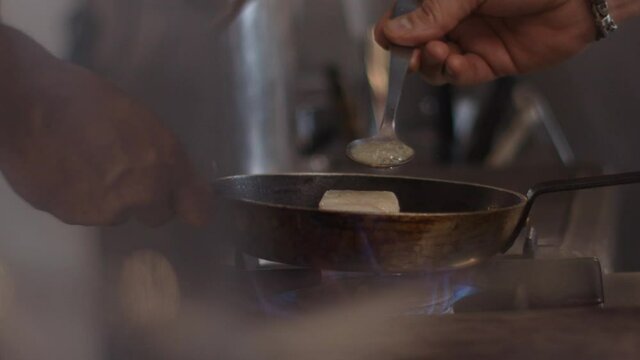 French Man prepares a dish in a pan with butter, cooking a fish, french cook, flavour a dish, seasoning a dish.