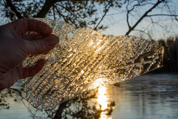 The piece of ice in the hand and sunset on the background, Finland