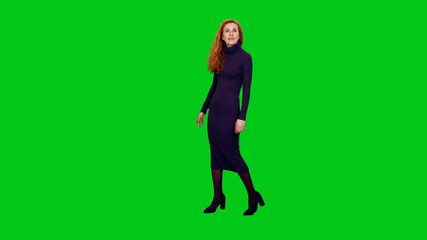 Elegant attractive red headed woman in long blue dress walking and looking at something on green...