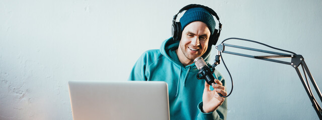 Handsome content creator streaming his live podcast using professional microphone at his broadcast...