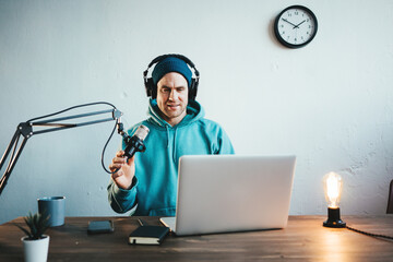 Man content creator streaming his live podcast using professional microphone at his broadcast studio