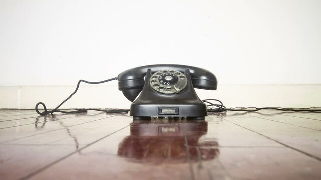  A vintage black phone ringing off the hook on a wooden floor stop motion loop 