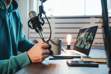 Content creator streaming his live podcast using professional microphone at his broadcast studio. Side view