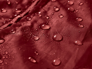 Water drops on waterproof membrane fabric. Detail view of texture of red waterproof cloth.