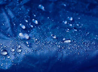 Water drops on waterproof membrane fabric. Detail view of texture of blue waterproof cloth.