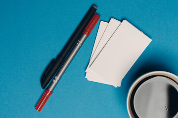 business cards on blue background and pen coffee cup top view
