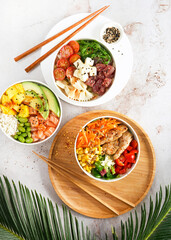Asian trendy poke bowls with salmon, tuna, heura soy protein vegan chicken, variety vegetables, served in bowl on tropical leaves. Healthy delicious vegan food. Diet, Protein Vegetarian Meals concept.