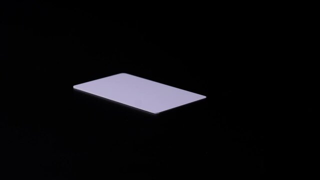 Stack of Proximity or RFID card white type thin, flexible, on black background. Stop motion.