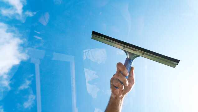 Fensterputzer putzt Glasscheibe mit Abzieher