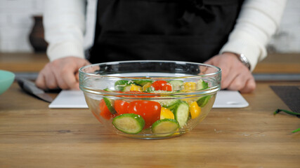 Fresh vegetables salad dish with cucumbers red cherry tomatoes yellow bell peppers sprinkled with sesame seeds in glass bowl, healthy eating food dieting and vegetarian concept