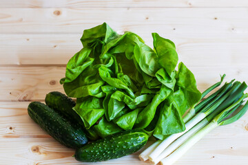 Green vegetables, healthy, fresh food, cucumbers, lettuce, green onions, photographed from above on a wooden background