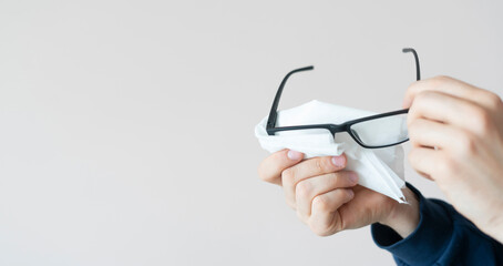 person's hands holding eye glasses and wipe the lenses, clean view sight