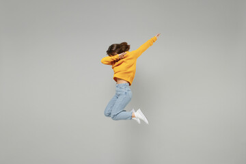 Fototapeta na wymiar Full length of young fun woman 20s wearing knitted yellow sweater jumping high doing dab hip hop dance hands move gesture youth sign hiding covering face isolated on grey background studio portrait..