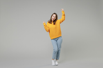 Full length of young smiling positive caucasian happy satisfied woman 20s in knitted yellow casual...