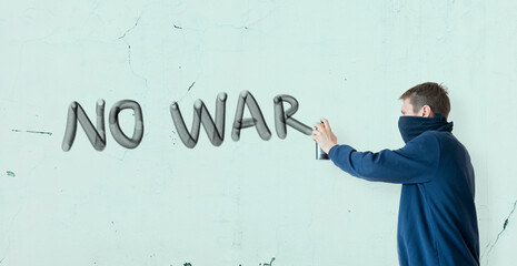 person male write with spray paint can the stop war statement on the wall, graffiti symbol concept