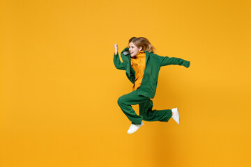 Fototapeta na wymiar Full length side view little blonde crazy excited overjoyed kid girl 12-13 years old in casual clothes jump high run isolated on yellow background children studio portrait Childhood lifestyle concept