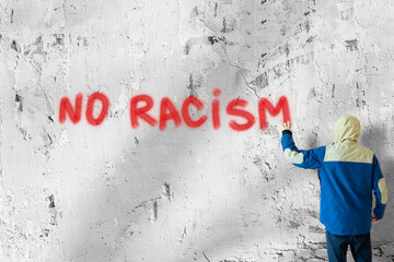 person male write with spray paint can the stop no racism  statement on the wall, graffiti symbol...