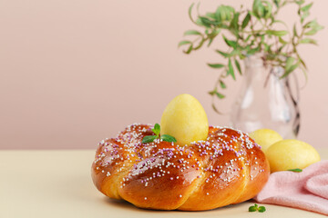 Happy Easter. Easter braided bread and Easter eggs on light peach and yellow background. Still life. Copy space.