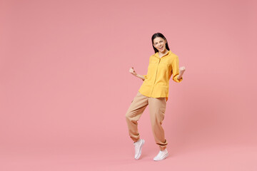 Fototapeta na wymiar Full length of young smiling brunette excited overjoyed attractive latin woman 20s in yellow casual shirt do winner gesture clench fist celebrating isolated on pastel pink background studio portrait.
