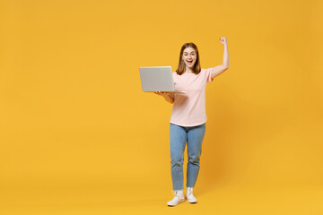 Full length of young caucasian student woman 20s in basic pastel pink t-shirt, jeans holding laptop...