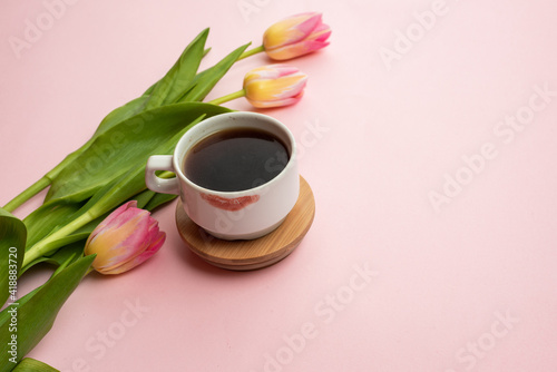 Spring background with beautiful colorful tulips, coffee and lipstick on pink table. Flat lay, top view, copy sapce. Spring concept, Mother's Day, March 8.