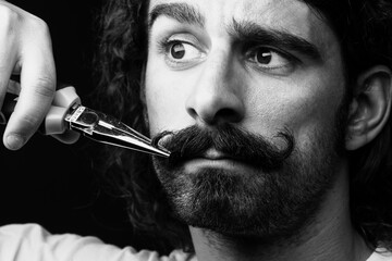 Obraz premium uomo si sistema il baffo con una pinza 