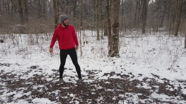 Male running in snowy winter forest, checking smartwatch fitness heart rate