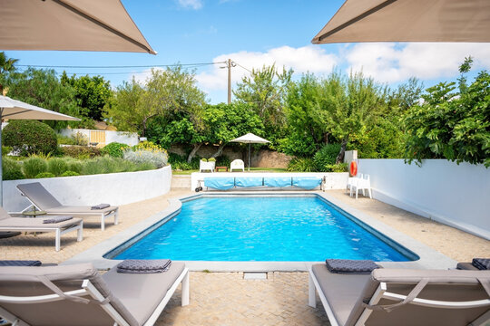 Loungers placed on the left and in the front of a pool with clean looking water on a sunny day.