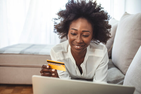 Shot Of A Young Woman Using A Laptop And Credit Card While Relaxing At Home. Keeping The Shopping Mall Close To Home. Shopping Spree Directly From The Sofa