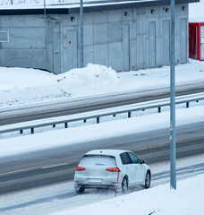 Cars driving on a highway in a blizzard with the road covered in snow and ice on a cold winters day.