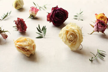 Dried roses and leaves arrangement on light linen background edited in warm instagram colors. floral patter. rustic style and country lifestyle. flat lay top view. international women day background 