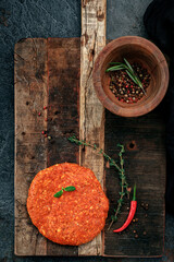 Raw spicy minced beef patties with red pepper on old wooden board for bbq