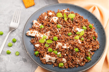 Quinoa porridge with green pea and chicken on ceramic plate on a gray concrete background. Top view, selective focus.