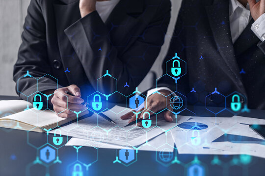Two businesswomen working on the project to protect cyber security of international company. Padlock Hologram icons over the table with documents.