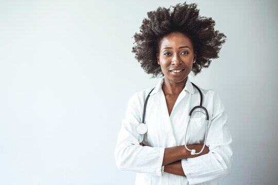 Shot of a female doctor standing confidently with her arms crossed. Smiling medical woman doctor. Isolated over grey background. Cheerful happy doctor with crossed hands on grey background.