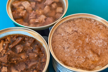 Pet nutrition concept. Cans of wet food for cats. Comparison between different types of tins of food for animals. Cubes, mousse, patè and fine flakes for kitten. Preservatives and scraps theme.